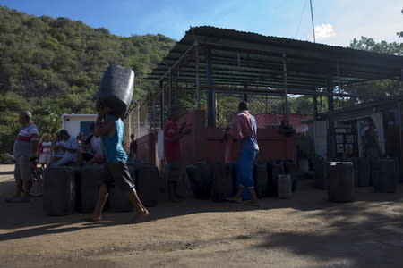 A man carries a container filled with gasoline, while others wait to fill their own at a gas station in the bay of Rio Caribe, a town near caribbean islands, in the eastern state of Sucre, Venezuela October 30, 2015. REUTERS/Carlos Garcia Rawlins