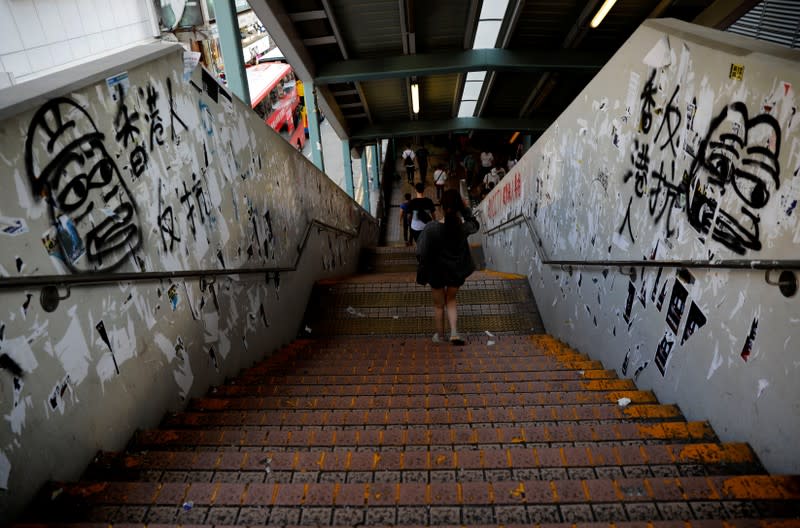 A woman walks past a passengers bridge bearing anti-government graffiti in Hong Kong