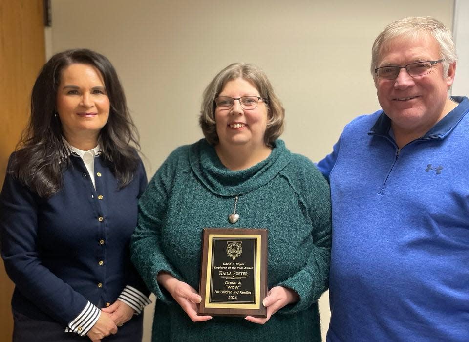 Muskingum County Adult and Child Protective Services Director Candy Emmert and retired director David Boyer present Kaila Foster with the 2024 David E. Boyer Employee of the Year Award. Foster is a child care worker at the Avondale Youth Center.