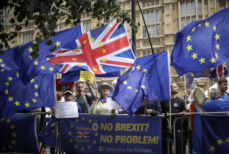 Remain supporters wave flags and hold signs as they protest opposite Parliament Square in London, Tuesday, Sept. 3, 2019. Parliament was reconvening Tuesday for a pivotal day in British politics as lawmakers challenge British Prime Minister Boris Johnson's insistence that the U.K. will leave the European Union on Oct. 31, 2019 even without a deal. (AP Photo/Matt Dunham)