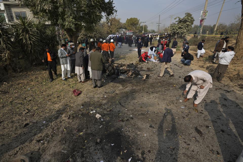 Security officials examine the wreckage of a car as rescue workers collect remains at the site of bomb explosion, in Islamabad, Pakistan, Friday, Dec. 23, 2022. A powerful car bomb detonated near a residential area in the capital Islamabad on Friday, killing some people, police said, raising fears that militants have a presence in one of the country's safest cities. (AP Photo/Anjum Naveed)