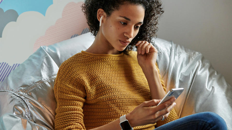 A woman wearing Apple AirPods and holding an iPhone