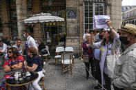 Anti heath pass demonstrators stage a protest next to a cafe terrace outside the Constitutional Council in Paris, Thursday, Aug. 5,2021. France's Constitutional Council is deciding on Thursday whether the health pass that is to open the doors and terraces to cafes, restaurants, trains and hospitals starting next week is in line with the nation's most cherished principles. (AP Photo/Michel Euler)