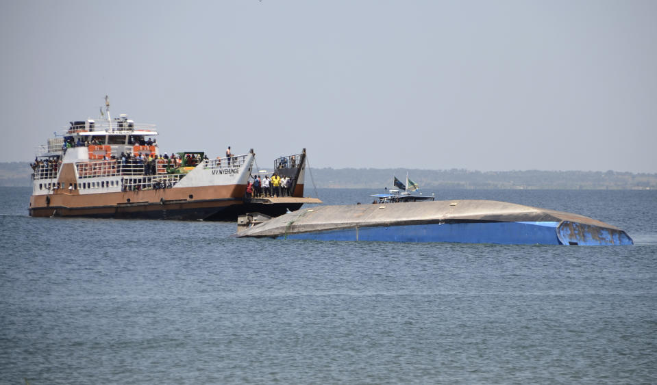 Passengers on the MV Nyehunge passenger ferry, left, look across at the capsized MV Nyerere passenger ferry as it lies upturned near Ukara Island, Tanzania Sunday, Sept. 23, 2018. Burials started Sunday of the more than 200 people who died when the ferry capsized on Lake Victoria, while the country's Defense Minister said no further survivors were likely to be found and search efforts had ended. (AP Photo/Andrew Kasuku)