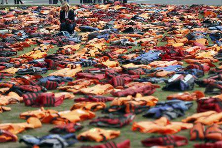 A woman looks at a display of lifejackets worn by refugees during their crossing from Turkey to the Greek island of Chois, Parliament Square in central London, Britain September 19, 2016. REUTERS/Stefan Wermuth