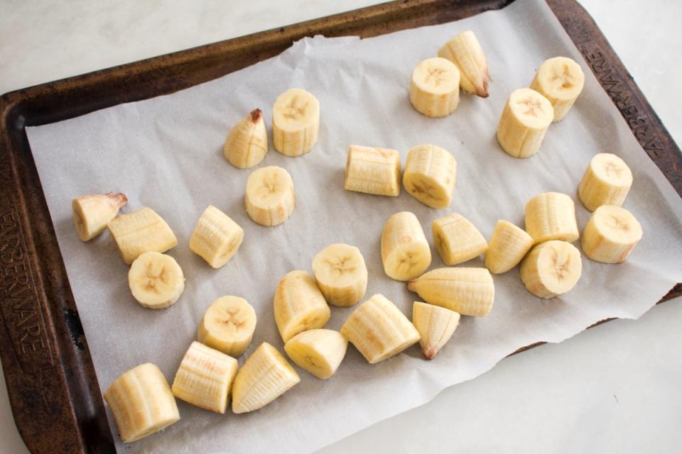 Frozen peeled pieces of banana on parchment paper on a tray