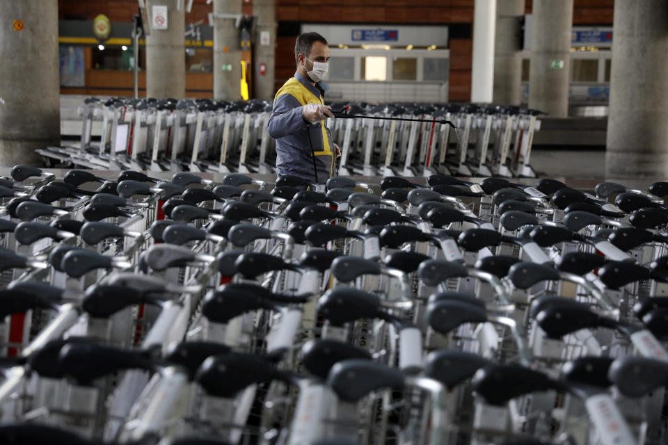 A worker disinfects trollies at terminal of Tehran's Imam Khomeini airport, Iran, Friday, July 17, 2020. The first Emirates flight arrived in Iran after nearly 5 months of suspension of the most airliners flights to the country due to the coronavirus outbreak, as Iranian officials at the airport say they are doing everything possible to ensure passengers are not infected, and isolate those with symptoms. (AP Photo/Vahid Salemi)