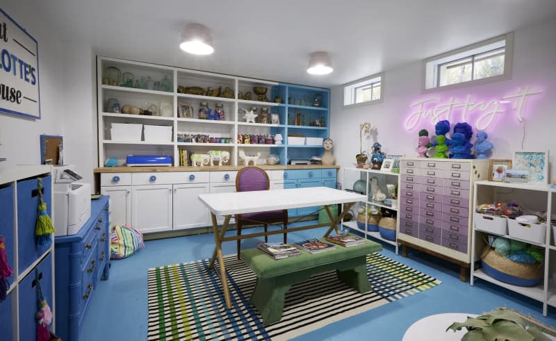 Colorful blue, white and purple craft room with neon signage and built in shelves.