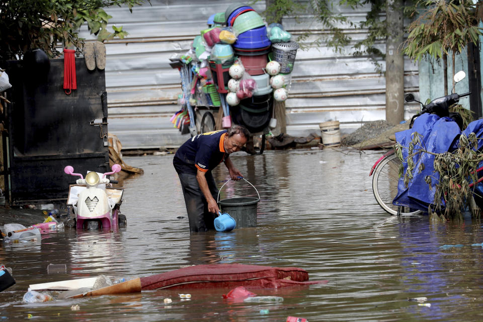 A man collects a water to clean his flooded house in Tanggerang on the outskirts of Jakarta, Indonesia, Friday, Jan. 3, 2020. Severe flooding in greater Jakarta has killed scores of people and displaced tens of thousands others, the country's disaster management agency said. (AP Photo/Tatan Syuflana)