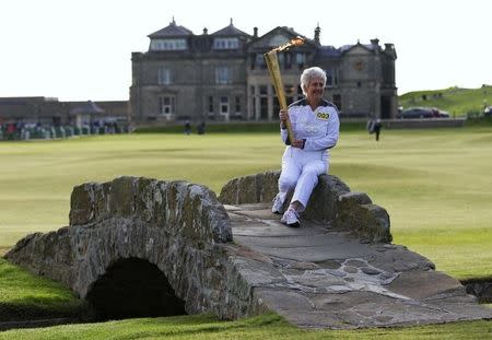 Torch bearer Louise Martin poses for photographers with the London 2012 Olympic torch on the Swilken Bridge next to the eighteenth tee on the Old Course at St Andrews in Scotland June 13, 2012. REUTERS/David Moir