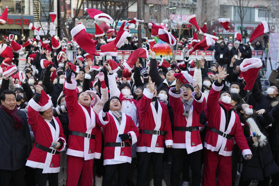 South Korean Prime Minister Han Duck-soo, fourth from right, and volunteers clad in Santa Claus costumes throw their hats in the air during a Christmas charity event before they deliver gifts for the underprivileged in Seoul, South Korea, Saturday, Dec. 24, 2022. (AP Photo/Lee Jin-man)