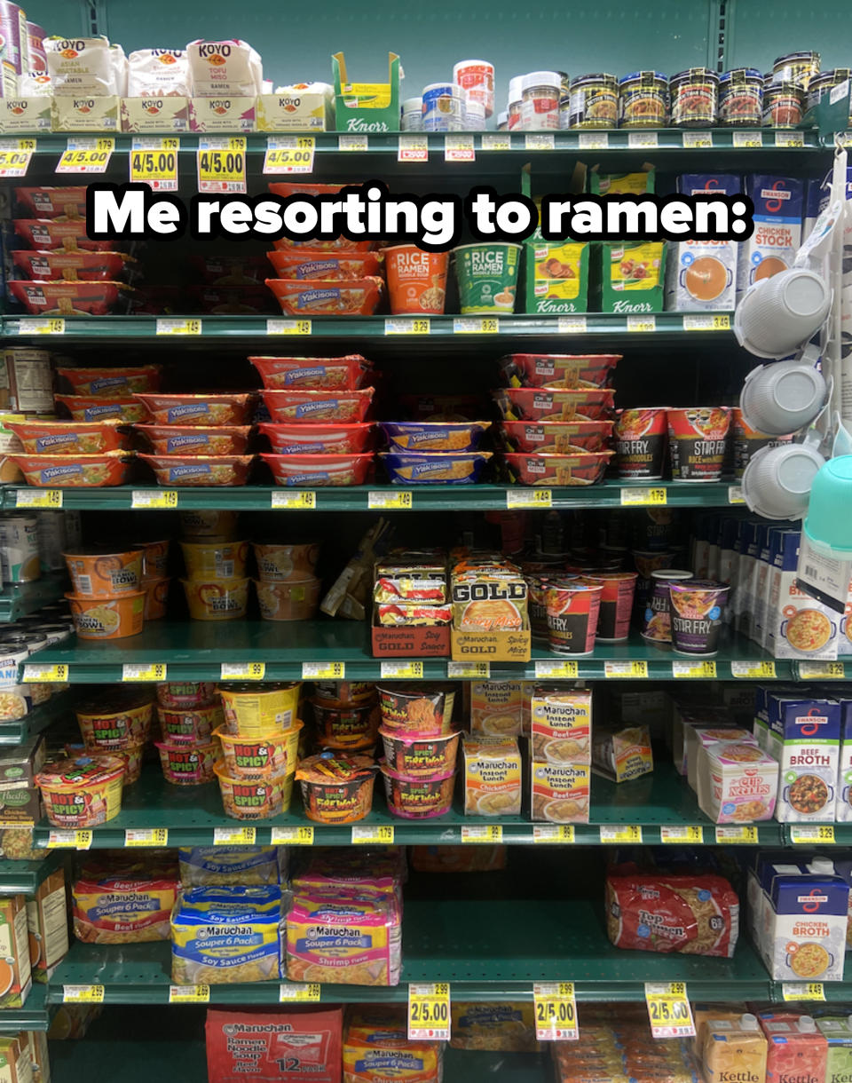 A supermarket shelf is filled with various brands of instant noodles, rice sides, and soup stocks, with price tags visible on each item