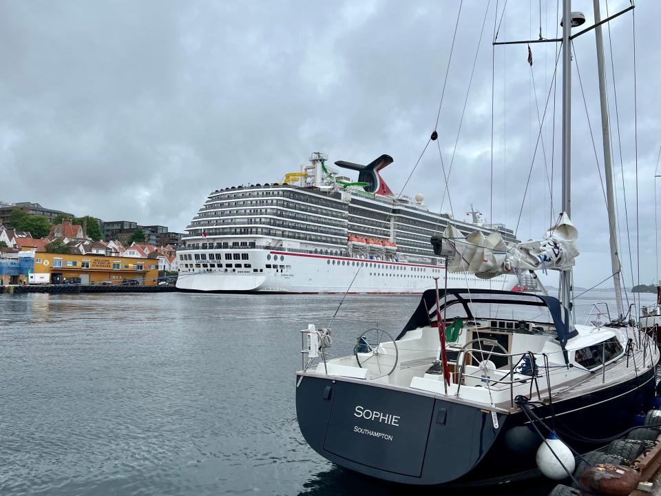 carnival pride in port in Stavanger with small sailboat in the foreground]