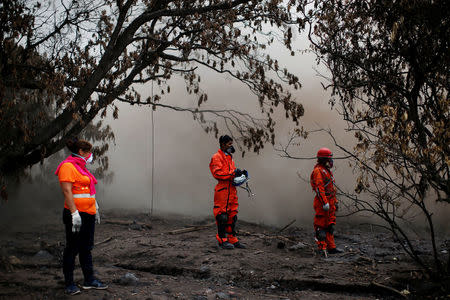 Eva Ascon, looks on next to rescue workers as they search for her rest of her family at the affected by the Fuego volcano at San Miguel Los Lotes in Escuintla Guatemala June 15, 2018. REUTERS/Carlos Jasso