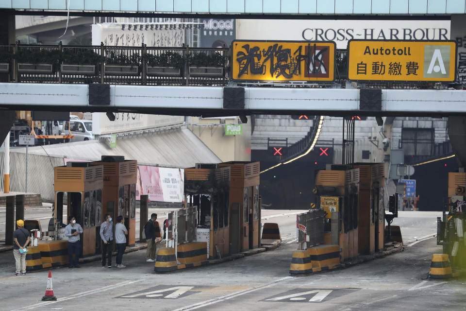 Workers inspect the damage from protesters on the toll booths of the Cross-Harbor Tunnel near the Polytechnic University in Hong Kong on Wednesday, Nov. 20, 2019. A small group of protesters refused to leave Hong Kong Polytechnic University, the remnants of hundreds who took over the campus for several days. They won't leave because they would face arrest. Police have set up a cordon around the area to prevent anyone from escaping. (AP Photo/Ng Han Guan)