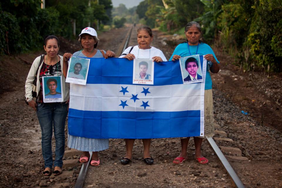 In this photo taken on Wednesday, Oct. 17, 2012, members of the Convoy of Central American Mothers, hold photographs of their missing relatives at the rail tracks in Amatlan de Los Reyes, Mexico. These women from Central America travel 2,800 miles through Mexico to search for their relatives who left for a better life and then disappeared on their journey to the U.S. (AP Photo)