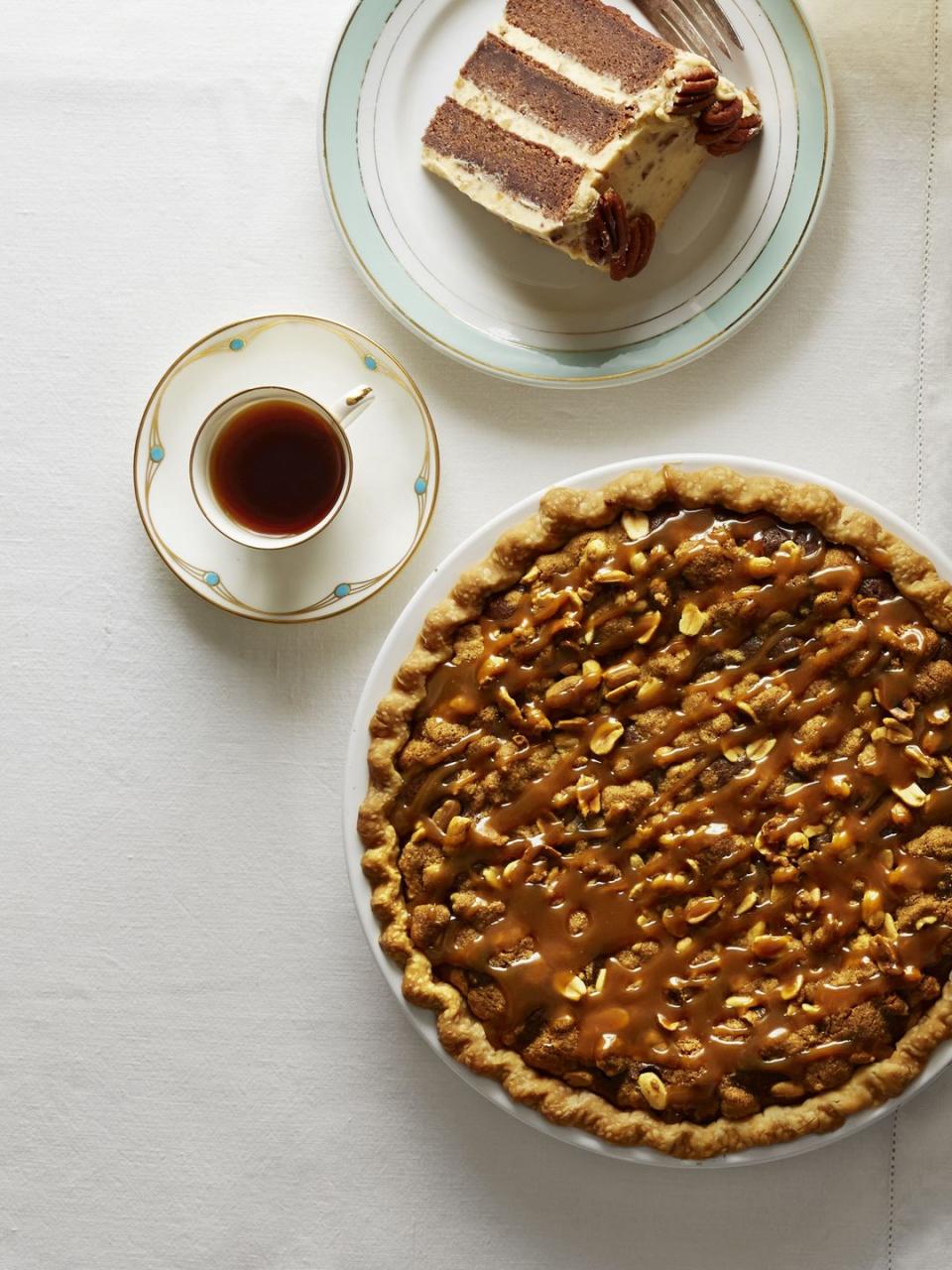 salted caramel peanut butter fudge pie in a white pie plate with small cups of coffee or tea