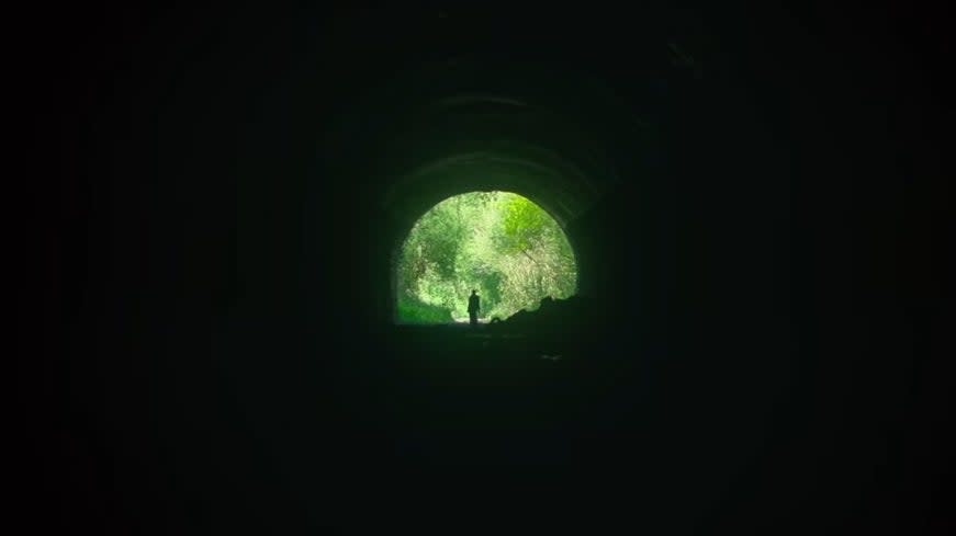 A mysterious figure standing at the end of a sewer tunnel in "Men"