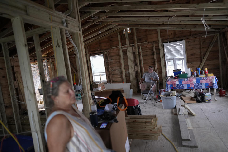 Jacquelyn and Timothy Velazquez sit inside the gutted shell of their 910 square foot two-bedroom home, which was damaged when Hurricane Ian's storm surge rose to within inches of the ceiling, in Fort Myers Beach, Fla., Wednesday, May 24, 2023. The couple has laid down new flooring, but is still battling with their insurance company to have the damage to the leaking roof covered, while waiting on permits for the renovation work. (AP Photo/Rebecca Blackwell)