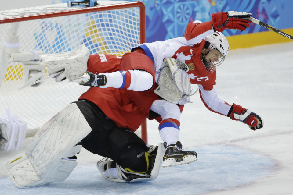 Yekaterina Smolentseva of Russia collides with Goalkeeper Florence Schelling of Switzerland during the 2014 Winter Olympics women's ice hockey quarterfinal game at Shayba Arena, Saturday, Feb. 15, 2014, in Sochi, Russia. (AP Photo/Matt Slocum)