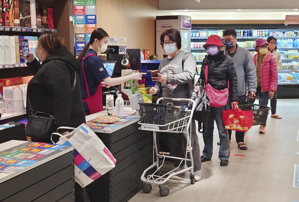 People wear face masks as they shop at a supermarket in Taipei, Taiwan, Monday, Feb. 20, 2023. Three years into the global pandemic, Taiwan said Monday, that people no longer have to wear masks at all times indoors though it is still keeping some restrictions in place. (AP Photo/Chiang Ying-ying)