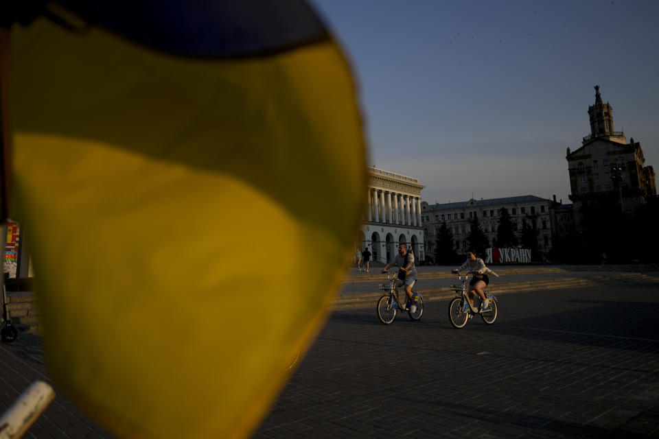 People ride bicycles in Kyiv, Ukraine, Friday, June 10, 2022. With war raging on fronts to the east and south, the summer of 2022 is proving bitter for the Ukrainian capital, Kyiv. The sun shines but sadness and grim determination reign. (AP Photo/Natacha Pisarenko)