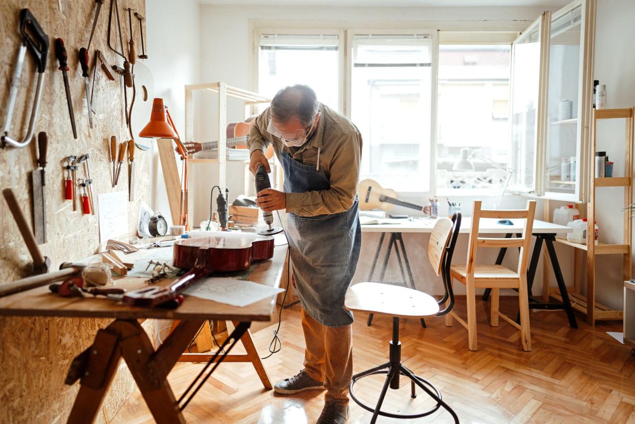 Man grinding homemade guitar for better shape