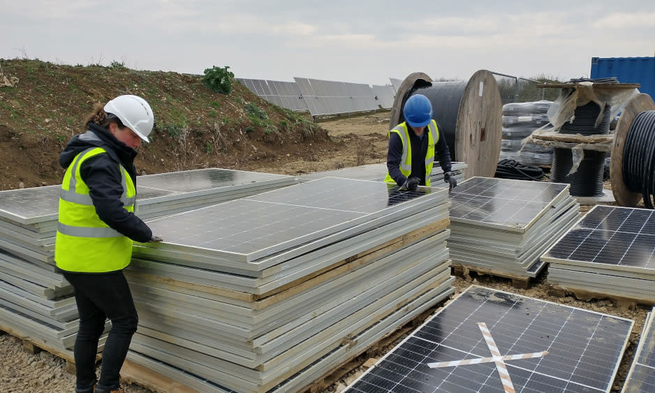 Imagen de dos personas examinando paneles solares dañados para su posible reciclaje.