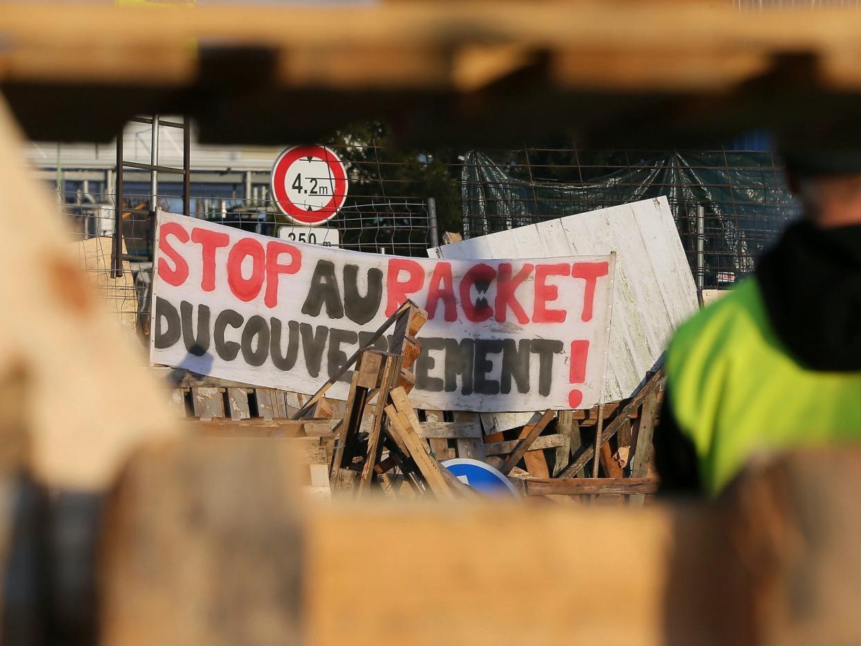 A demonstrator stands in front of a barricade set up by the yellow vests to block the entrance of a fuel depot in Le Mans, western France, on Tuesday: AP