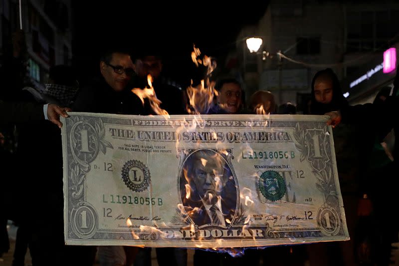 Palestinian demonstrators burn an illustration of a U.S. dollar banknote with the picture of President Donald Trump during a protest against Trump's Mideast peace plan, in Ramallah in the Israeli-occupied West Bank