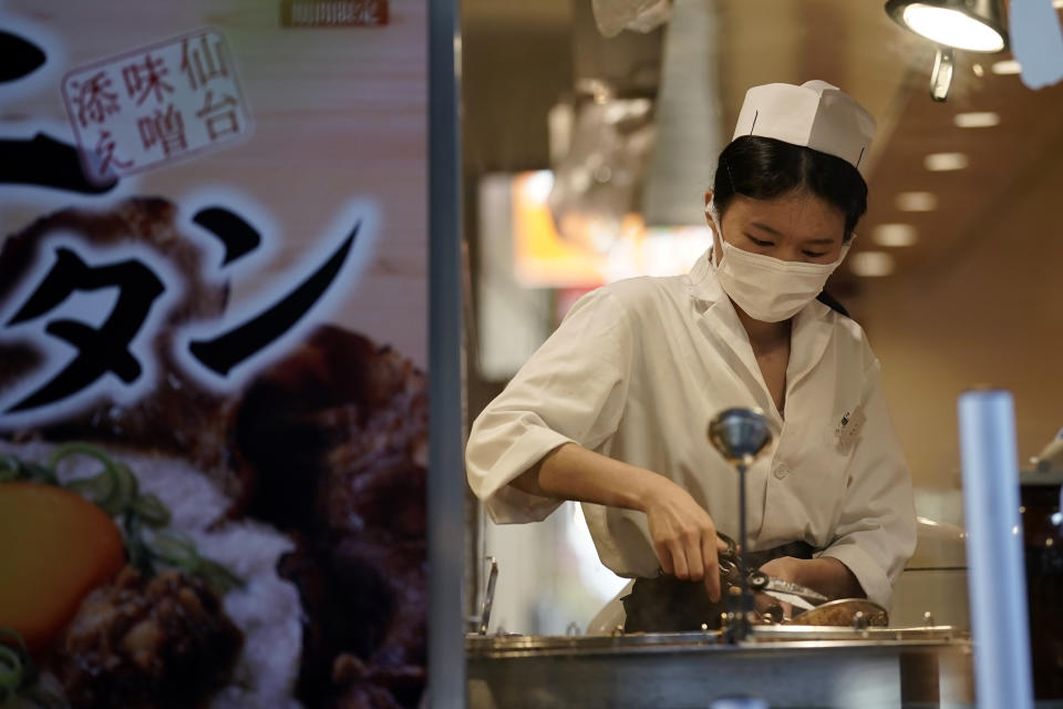 A restaurant employee wearing a face mask to help curb the spread of the coronavirus prepare a dish for a customer, Thursday, Sept. 10, 2020, in Tokyo. The Japanese capital confirmed more than 270 coronavirus cases on Thursday. (AP Photo/Eugene Hoshiko)