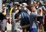 FILE - Tennis fans drink water on a hot day at the USTA Billie Jean King National Tennis Center during the second round of the U.S. Open tennis tournament, Aug. 29, 2018, in New York. An Associated Press analysis shows the average high temperatures during the U.S. Open and the three other Grand Slam tennis tournaments steadily have grown hotter and more dangerous in recent decades. (AP Photo/Kevin Hagen)