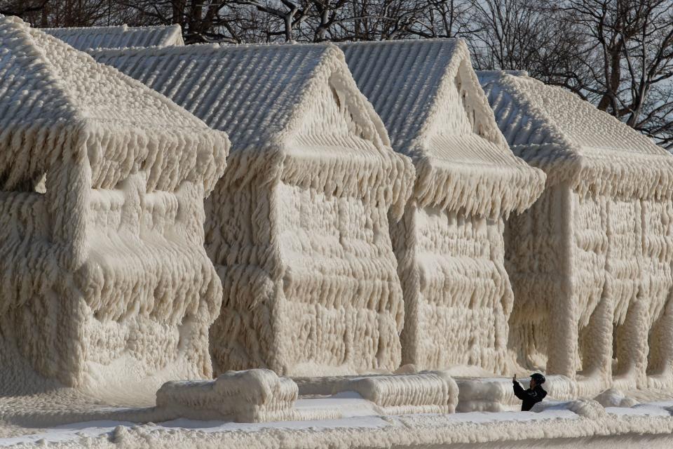 In silhouette, someone takes photos of the frozen houses on Crystal Beach.