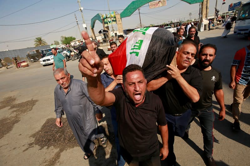 Mourner reacts as others carry the coffin of a demonstrator who was killed at anti-government protests, during a funeral in Najaf