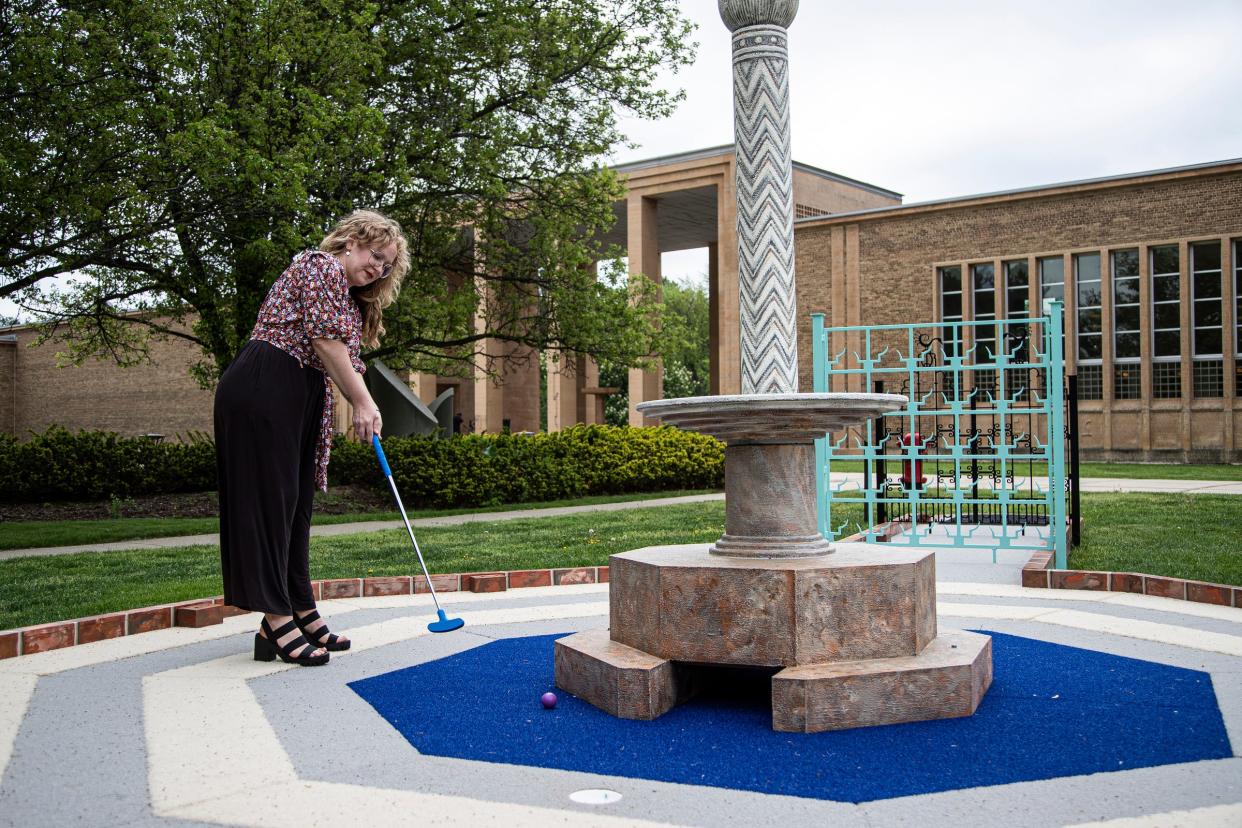 Lyla Catellier, Curator of Public Programming demonstrates playing the Hole 1: Gateway at the Cranbrook on the Green, an artist-designed mini-golf course outside of the Cranbrook Art Museum in Bloomfield Hills on Friday, May 20, 2022.