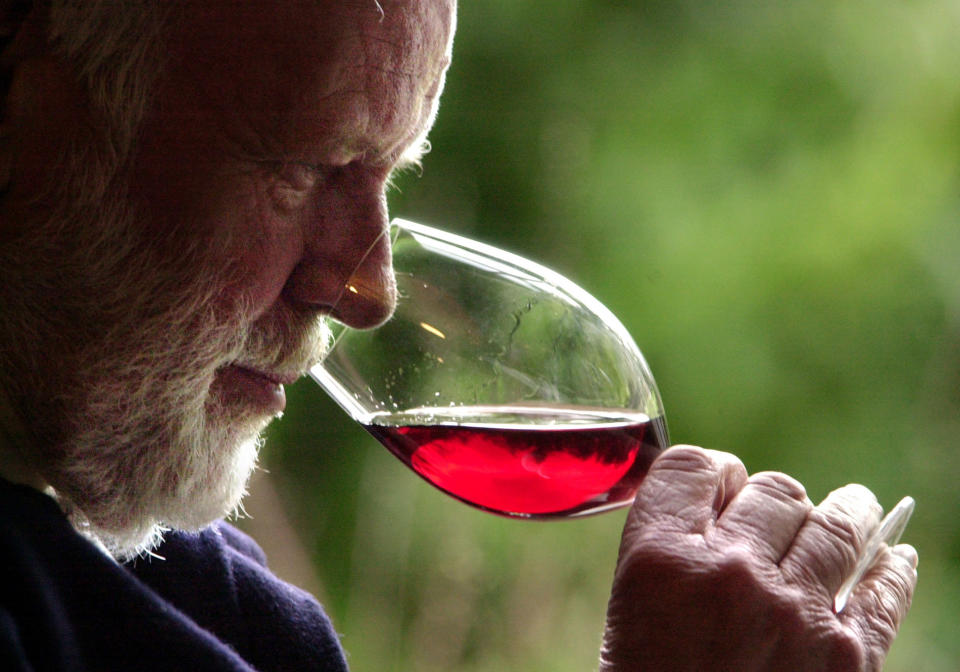 FILE--In this Feb. 23, 2004, file photo, winemaker David Lett savors the bouquet from a glass of Pinot Noir at his Eyrie Vinyards home in Dundee, Ore. Some Oregon lawmakers and winery owners are scrambling to help a dozen vineyards owners who face having 2,000 tons of grapes wither on the vine, unsold, after a California winemaker abruptly cancelled contracts to buy them, claiming they were tainted from some from the summer's wildfires.(AP Photo/Don Ryan)