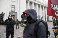 A protester in a gas mask takes part in a rally in front of the parliament building in Kyiv, Ukraine, Tuesday, March 17, 2020. Protesters demanded lawmakers to stop working amid nation-wide quarantine in order to prevent hastily adopting unpopular laws. In an additional set of measures preventing the spread of the new coronarivus, Ukrainian authorities ruled to close public places except food markets, pharmacies and gas stations starting from Tuesday in Kyiv and other regions, and restrict the use of public transport from Kyiv to other Ukrainian cities. For most people, the new coronavirus causes only mild or moderate symptoms. For some it can cause more severe illness, especially in older adults and people with existing health problems. (AP Photo/Efrem Lukatsky)
