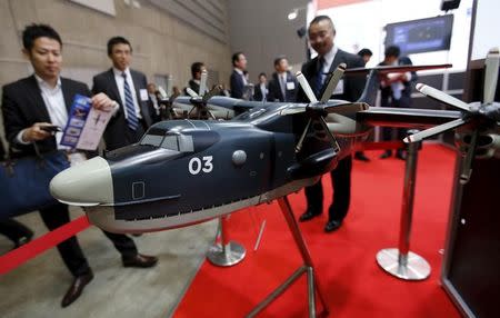 Visitors look at a model of Japan Maritime Self-Defense Forces US-2 search-and-rescue amphibian plane, manufactured by ShinMaywa Industries Ltd, during the MAST Asia 2015, defence exhibition and conference in Yokohama, south of Tokyo May 13, 2015. REUTERS/Toru Hanai/File Photo