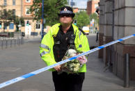 <p>A police officer carries a floral tribute close to the Manchester Arena, the morning after a suicide bomber killed more than a dozen people as an explosion tore through fans leaving a pop concert in Manchester England Tuesday May 23, 2017. (Danny Lawson/PA via AP) </p>
