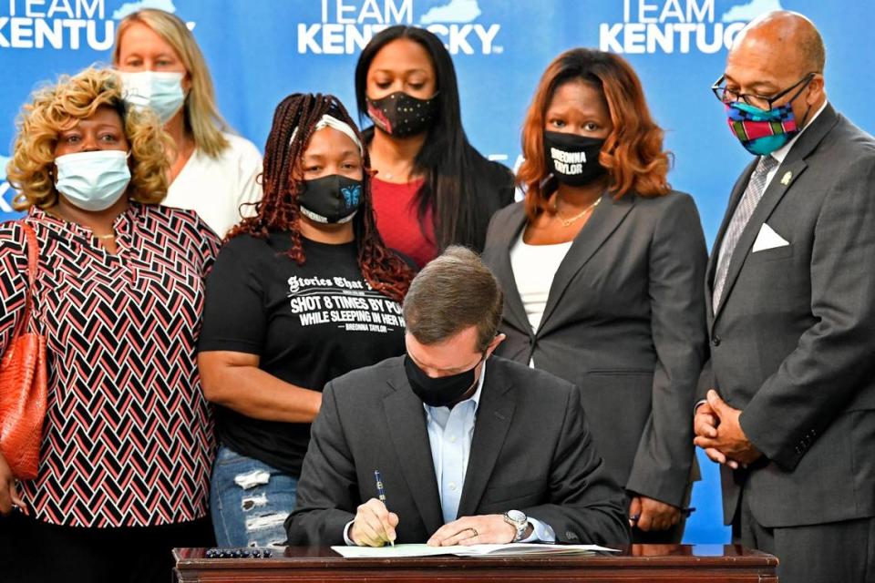FILE - Kentucky Gov. Andy Beshear signs a bill creating a partial ban on no-knock warrants, Friday, April 9, 2021, at the Center for African American Heritage Louisville, Ky. At the signing is Tamika Palmer, the mother of Breonna Taylor, behind Governor left. Democratic lawmakers in California, Maryland and Washington passed far-reaching policing reforms this year in response to the 2020 killing of George Floyd in Minnesota. But the first full year of state legislative sessions since the killing sparked a summer of racial justice protests produced a far more mixed response in the rest of the country.(AP Photo/Timothy D. Easley, File)