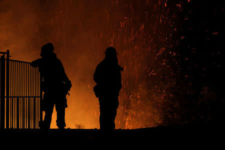 Burning embers swirl around firefighters as they stand guard at a home while battling the Carr Fire, west of Redding, California, U.S., July 27, 2018. REUTERS/Fred Greaves