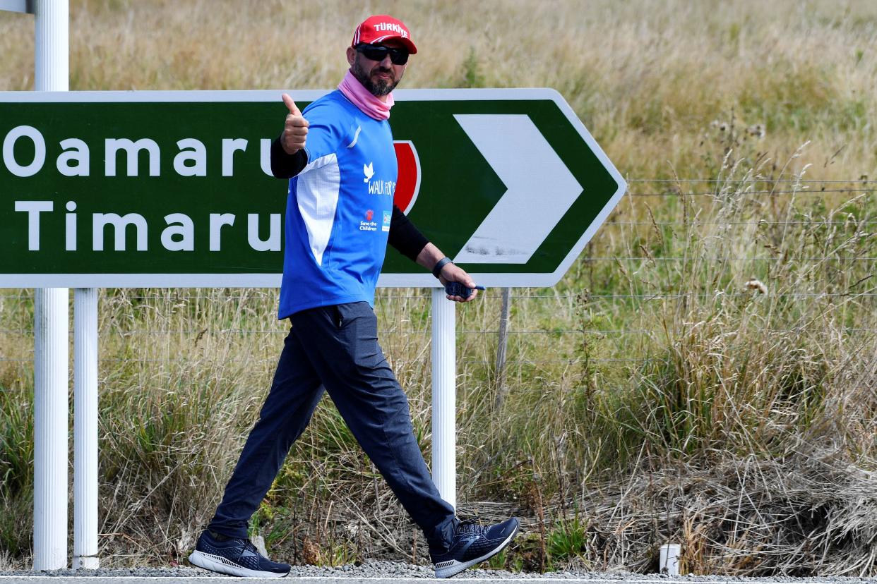 Temel Atacocugu, a survivor of the twin mosque shootings, waves as he walks towards Christchurch on March 4, 2022 during his 224-mile journey.