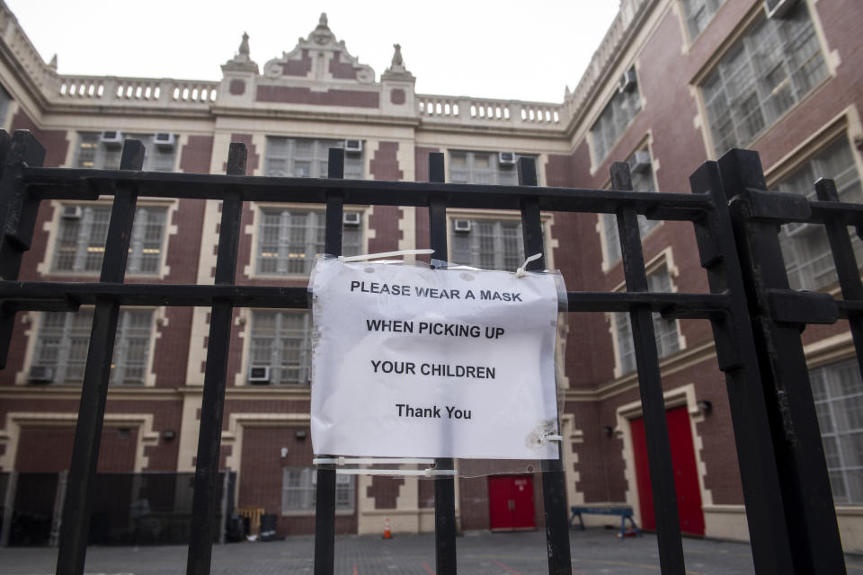 A sign encouraging people to wear masks when picking up their children is posted outside M363 The Neighborhood school in the East Village of Manhattan, on Tuesday, Dec. 21, 2021, in New York. (AP Photo/Brittainy Newman)