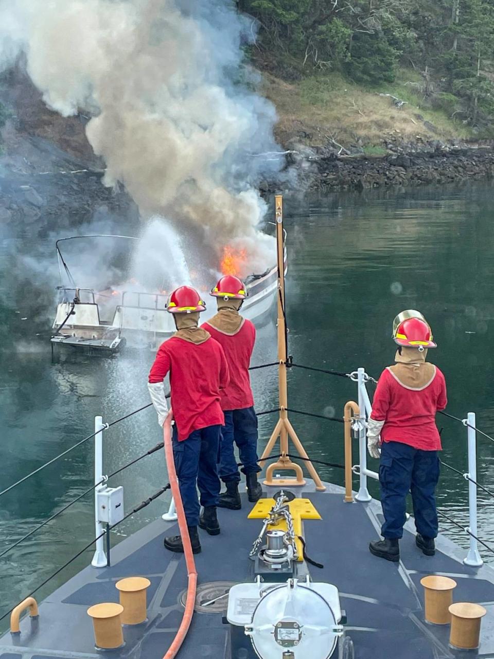 U.S. Coast Guard crew members from the Bellingham-based 87-foot cutter Sea Lion extinguish a boat fire Wednesday morning, June 15, in the San Juan Islands. Two people on board at the time were not seriously injured in the incident.