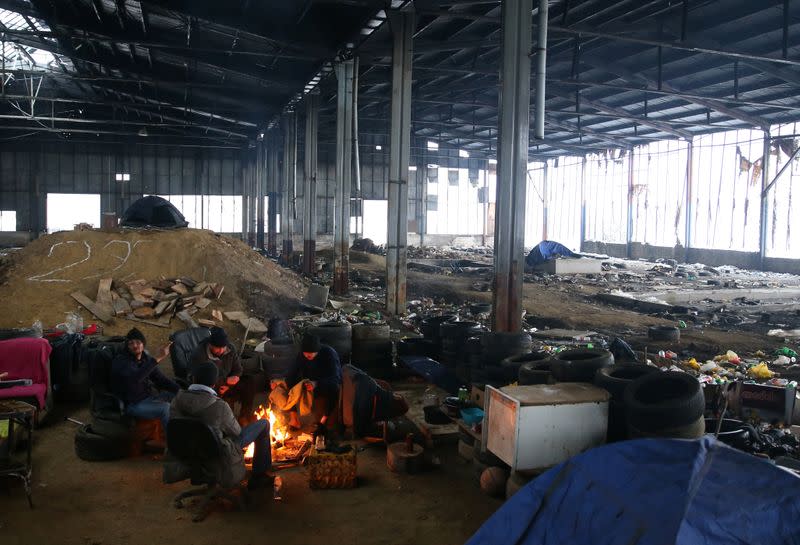 Migrants warm up in an abandoned factory near Velika Kladusa