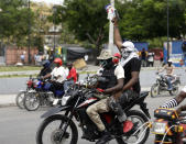 Armed off-duty police officers ride motorcycles and fire their weapons in the air during a protest over pay and working conditions, in Port-au-Prince, Haiti, Sunday, Feb. 23, 2020. Off-duty police officers and their supporters exchanged fire for nearly two hours with members of the newly reconstituted Haitian army in front of the national palace. (AP Photo/Dieu Nalio Chery)