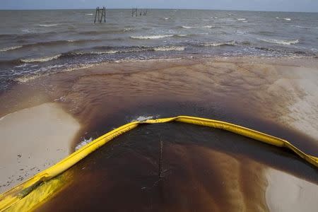 A protective boom is seen as oil from the Deepwater Horizon spill recedes back into the Gulf of Mexico after washing into a drainage canal in Waveland, Mississippi July 7, 2010. REUTERS/Lee Celano