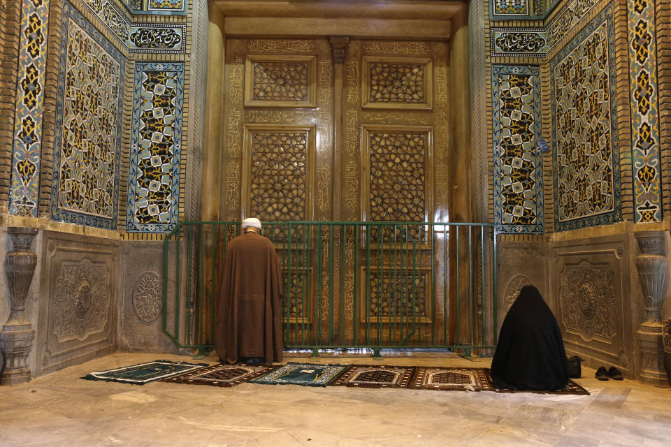 A cleric and a woman pray behind a closed door of Masoume shrine in the city of Qom, some 80 miles (125 kilometers) south of the capital Tehran, Iran, Monday, March 16, 2020. On Monday, Iran closed the Masoume shrine, a major pilgrimage site in the city of Qom, the epicenter of the country's new coronavirus outbreak. Authorities were already restricting access and barring pilgrims from kissing or touching the shrine, but it had remained open. (AP Photo)