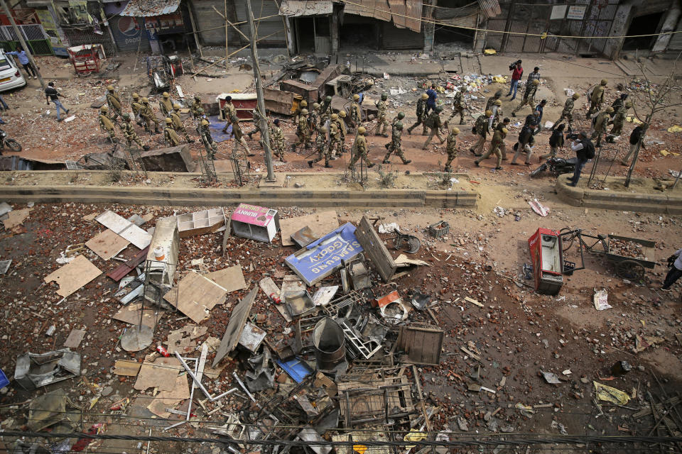 Indian paramilitary soldiers patrol a vandalized street in Tuesday's violence in New Delhi, India, Thursday, Feb. 27, 2020. India accused a U.S. government commission of politicizing communal violence in New Delhi that killed at least 30 people and injured more than 200 as President Donald Trump was visiting the country. The violent clashes between Hindu and Muslim mobs were the capital's worst communal riots in decades and saw shops, Muslim shrines and public vehicles go up in flames. (AP Photo/Altaf Qadri)