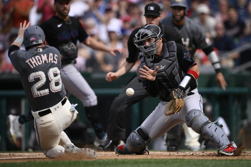 Washington Nationals' Lane Thomas (28) slides home to score on a single by Tres Barrera against Miami Marlins catcher Nick Fortes, right, during the second inning of a baseball game, Saturday, July 2, 2022, in Washington. (AP Photo/Nick Wass)